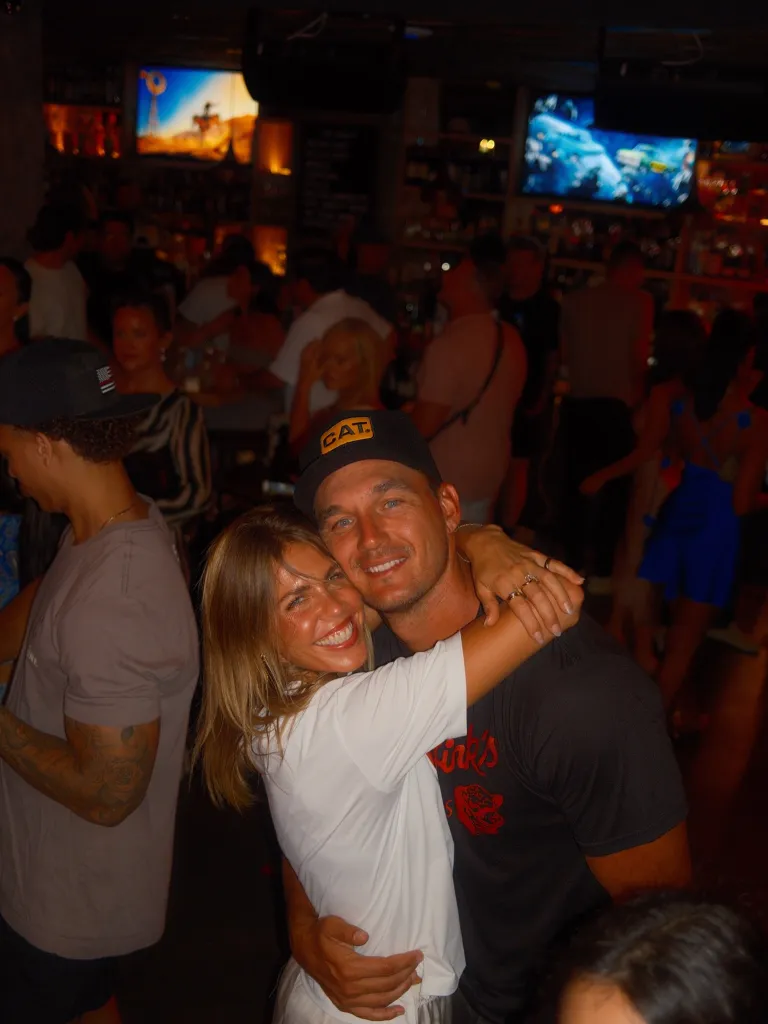 Tyler Cameron and fiancée Tate Madden embrace in a crowded bar.