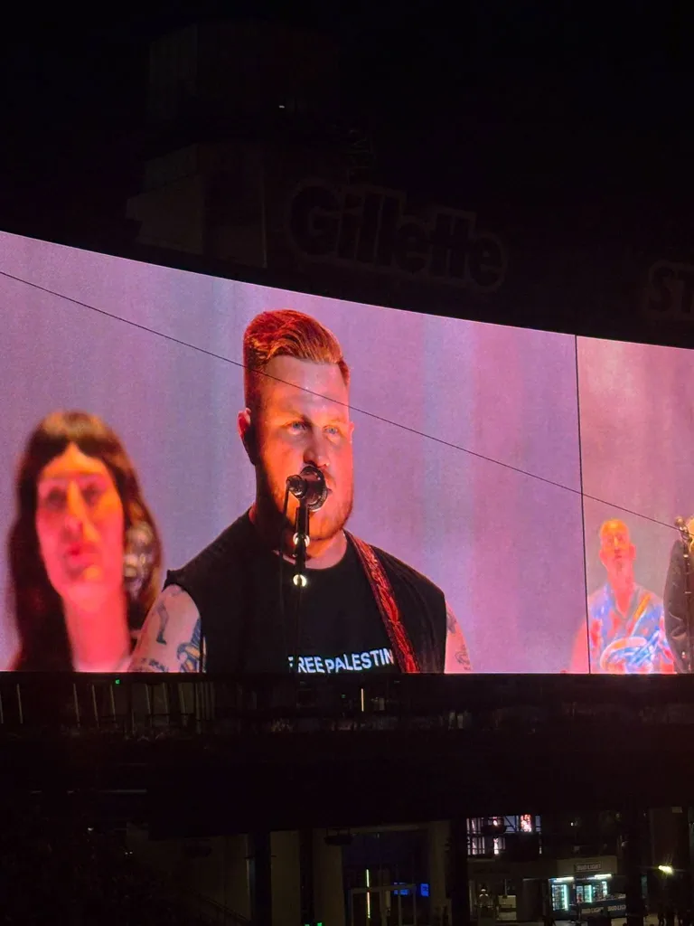 Zach Bryan wearing a 'Free Palestine' shirt while performing at a concert.
