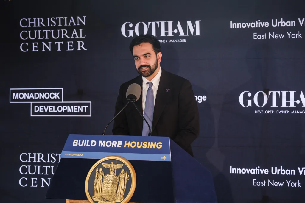 New York City Mayor Zohran Mamdani speaks at a podium with the text 
