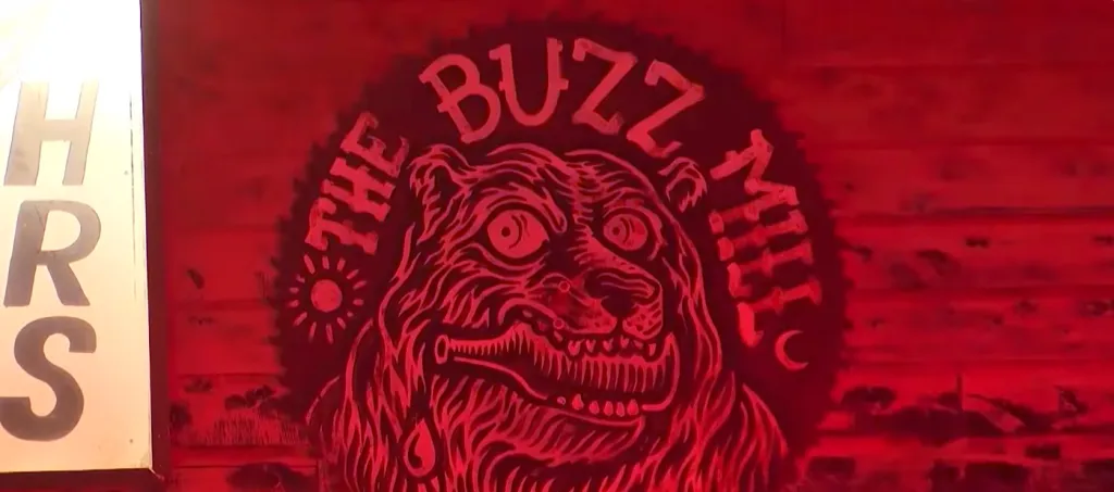 Illustration of the logo for The Buzz Mill, featuring a wild-eyed bear biting a bottle.